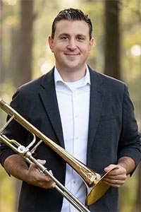 Headshot of Phil Pandori holding a trombone.