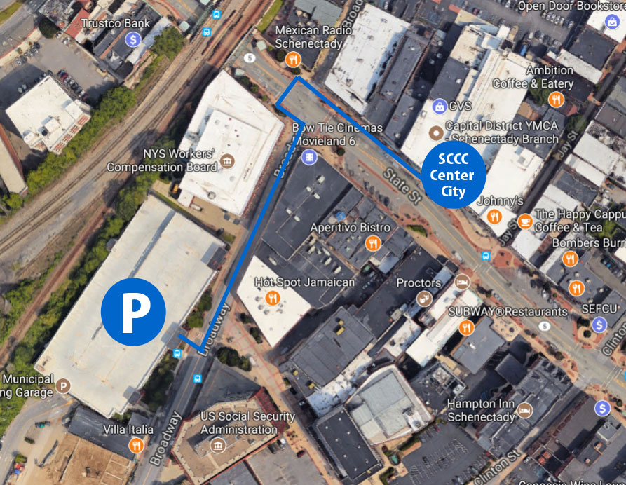 Aerial map of downtown Schenectady showing the Broadway Parking Garage marked with a large letter P. Then there is a blue line that follows Broadway north to State Street, turns right onto State Street and stops at approximately 433 State Street where there is a digitally imposed marker for SCCC Center City.