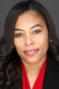 Headshot of Dr. Nicole Reaves, wearing a red blouse and a black suit jacket. 