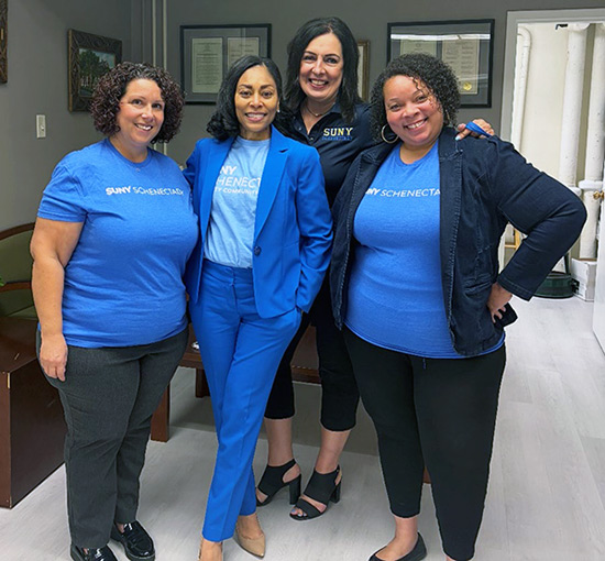 Four women stand together, all wearing SUNY Schenectady attire.
