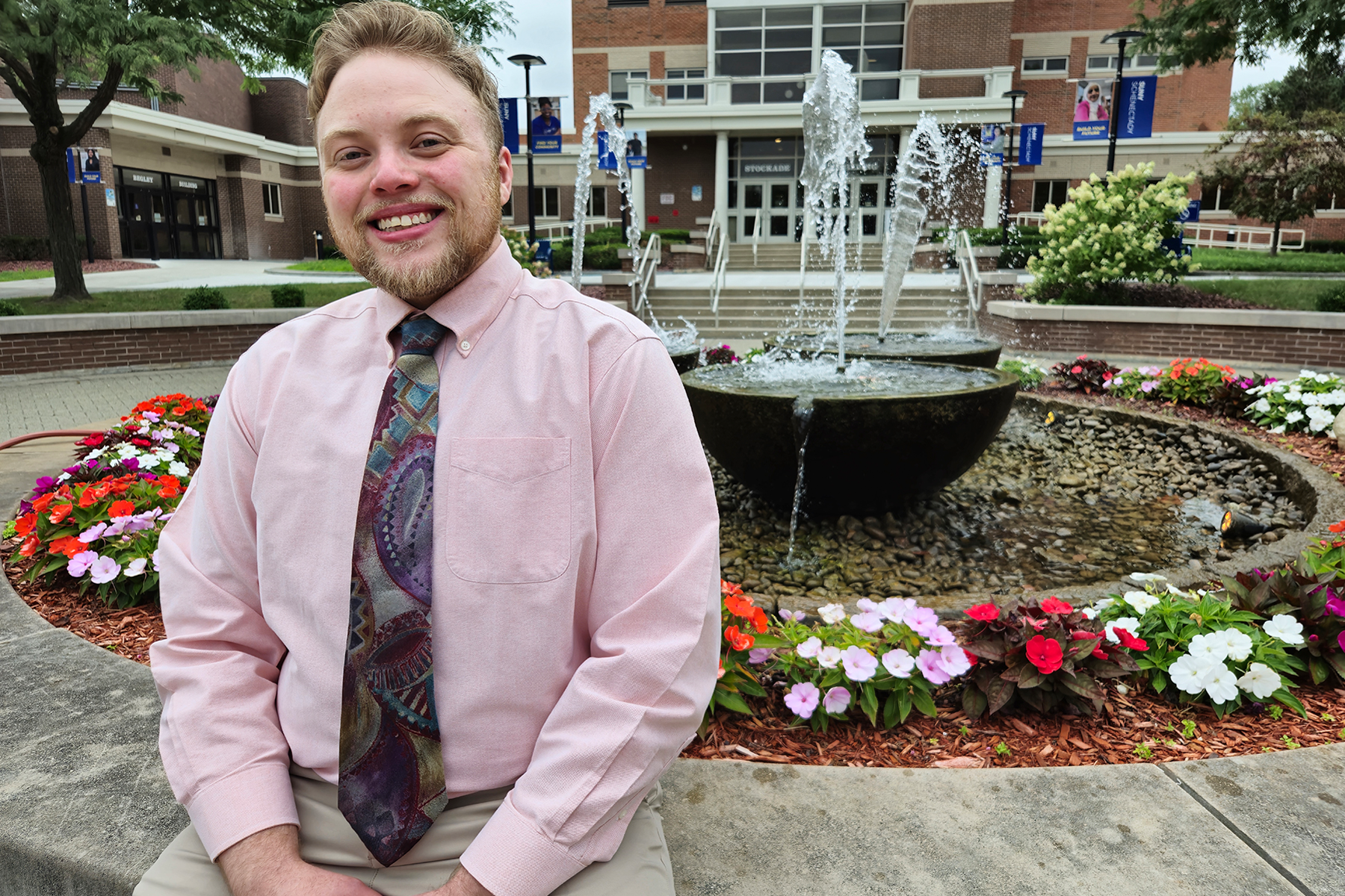 James Harris sitting outside near fountain in The Quad, smiling