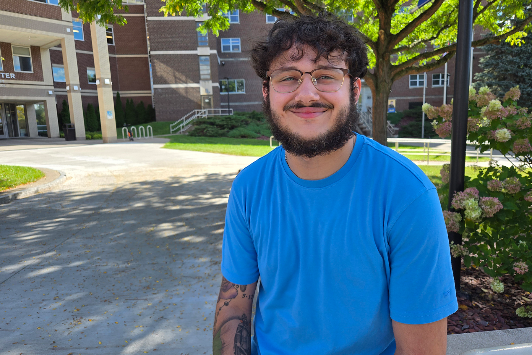 Matthew Perez sitting outside in The Quad, smiling