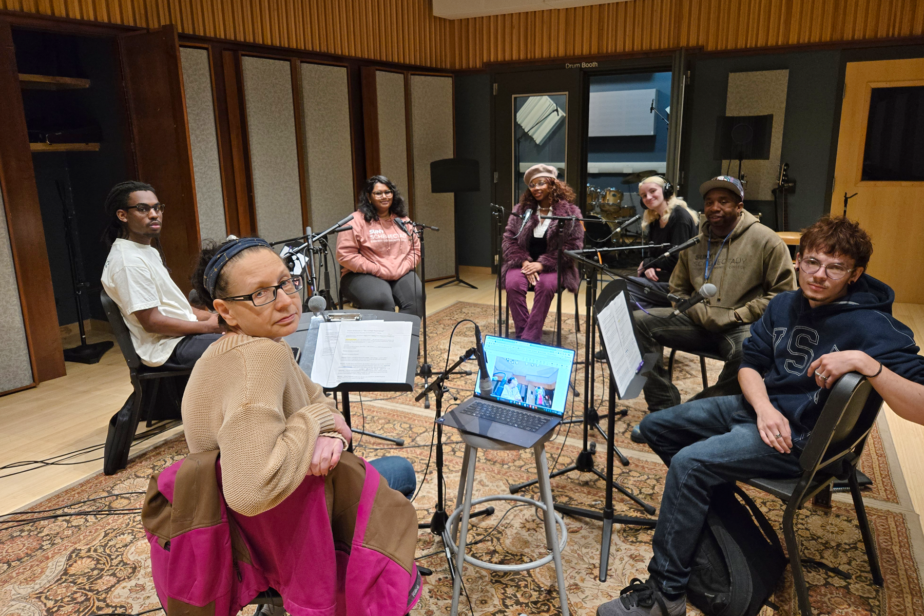 Podcast co-hosts and guests seated in front of microphones in recording studio