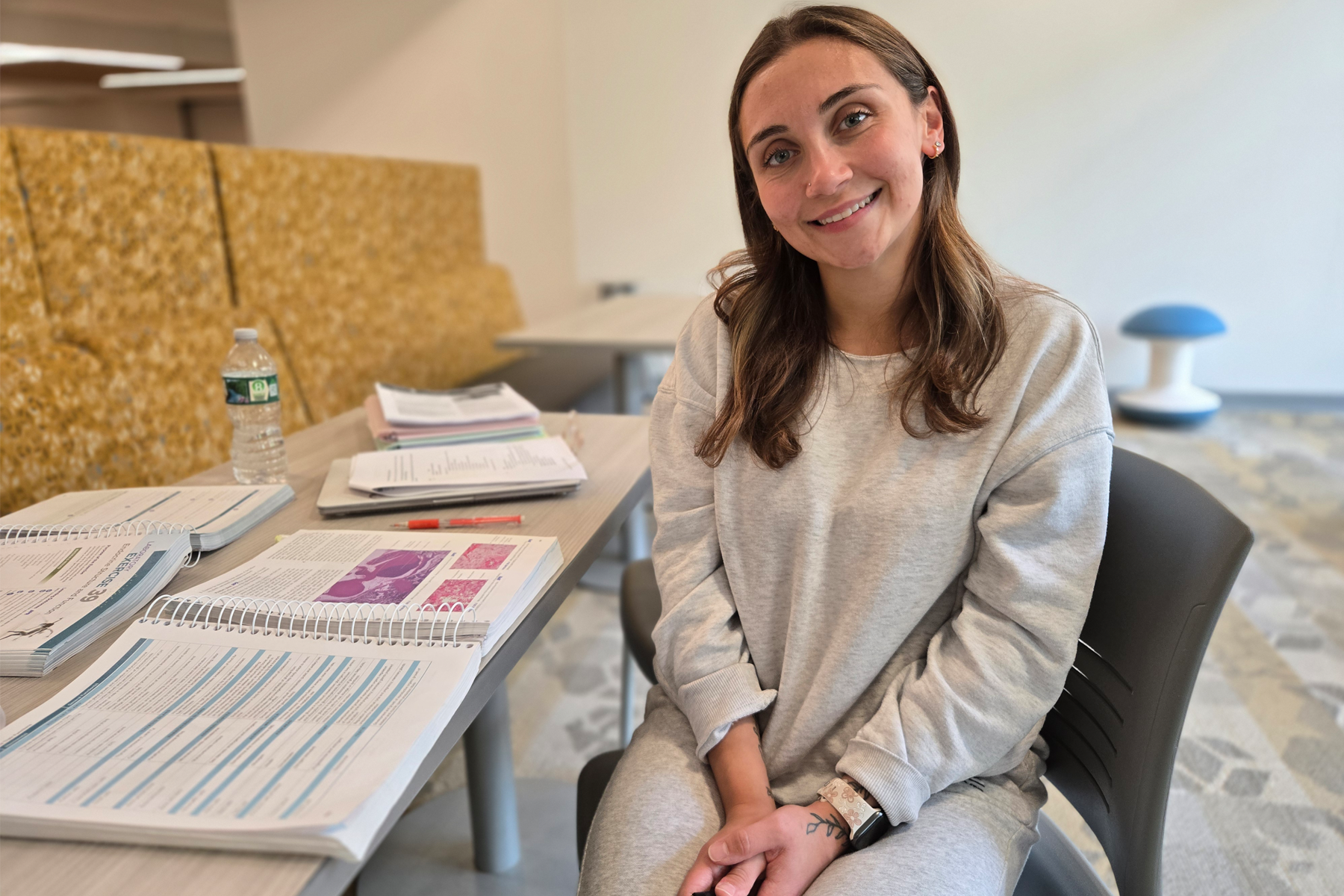 Sydney Sciocchetti sitting at table in Library, with books in front of her