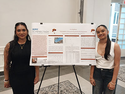 Two Early College High School students stand with their poster presentation.