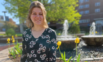 Lydia Hulbert sitting by the fountain in the Quad.