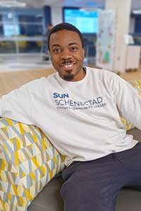 Adult student in a SUNY Schenectady sweatshirt, sitting in the Begley Learning Commons.