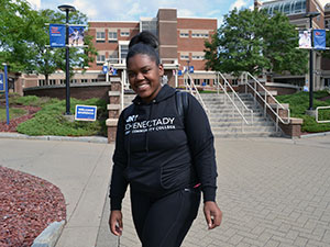 Student in a SUNY Schenectady sweatshirt, standing in the Quad.