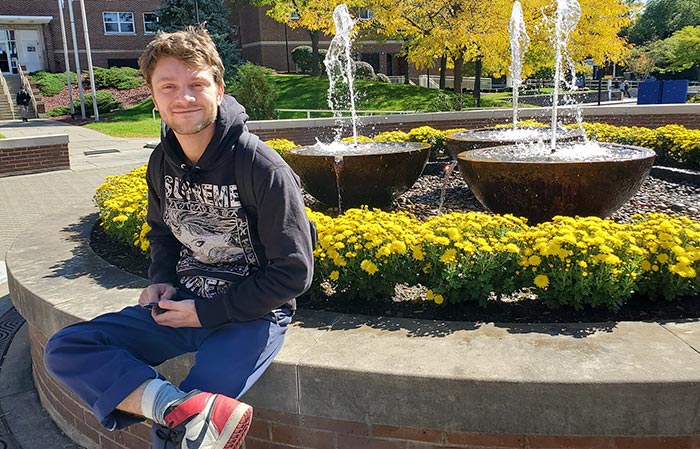 Student sitting on the edge of the Quad fountain on a beautiful fall day.