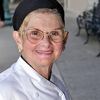 Joan Dembinski in a chef's coat and cap.