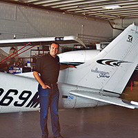 Jamie Hildenbrandt standing in an airplane hanger in front of a plane.