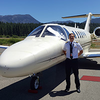 Joshua Ross in a pilot's uniform, standing in front of a plane.