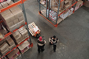 Overhead shot of two people working in a large warehouse.