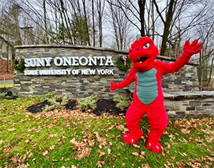 SUNY Oneonta campus sign, with their mascot, a red dragon, standing beside it. 