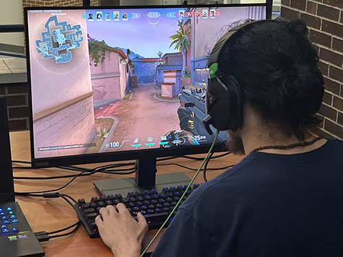 Student playing an online game, over the shoulder perspective looking at screen.  