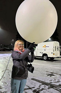 Erin Potter holding a weather balloon outside in the winter.