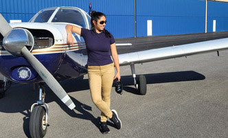 Female aviation students leans against a small aircraft at the Schenectady Airport.