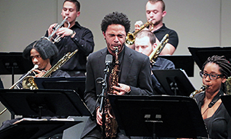 Students on stage at a concert, focus on a student playing a sax.