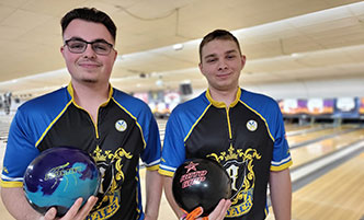 Two student bowlers in their Royals jerseys, holding bowling balls. 