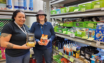 Food pantry student worker and staff member holding products in the food pantry.