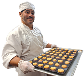 Culinary student in uniform, holding a tray of baked goods.