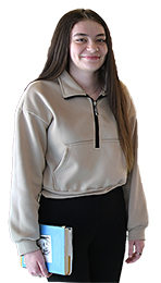 White female student, with long dark hair, wearing a tan sweatshirt and black leggings. 