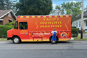 Fred Santiago standing in front of his food truck, Yago's Munchie Machine.
