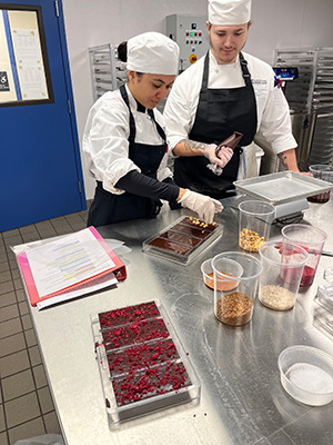 Two culinary students work in the confections lab making chocolate bars.