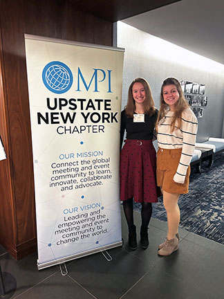 Students standing in front of the MPI Upstate NY Chapter banner. 