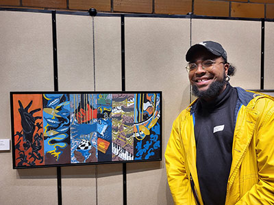 SUNY Schenectady alumnus, Tayron Lopez '16 (Taiitan), standing with one of his pieces at the Rise Gallery.