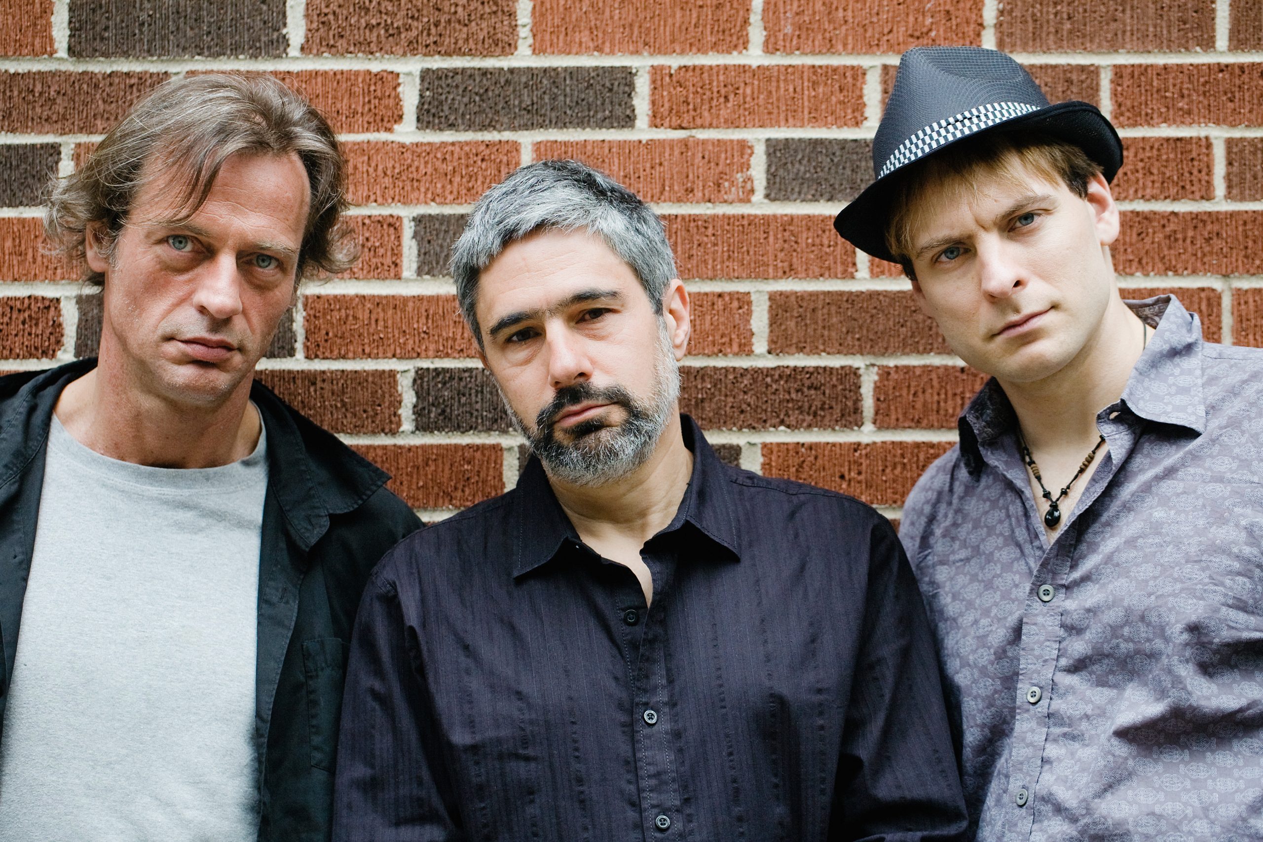 The three members of Pilc Moutin Hoenig Trio leaning against a brick wall. 