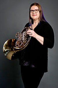 Katy Svatek holding a French horn. 