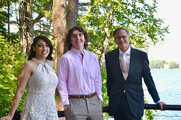 Three members of The Quarry Project, Areli Mendoza-Pannone, soprano, Robert Frazier, bass-baritone, and Mark Evans, standing on a deck in front of a lake.