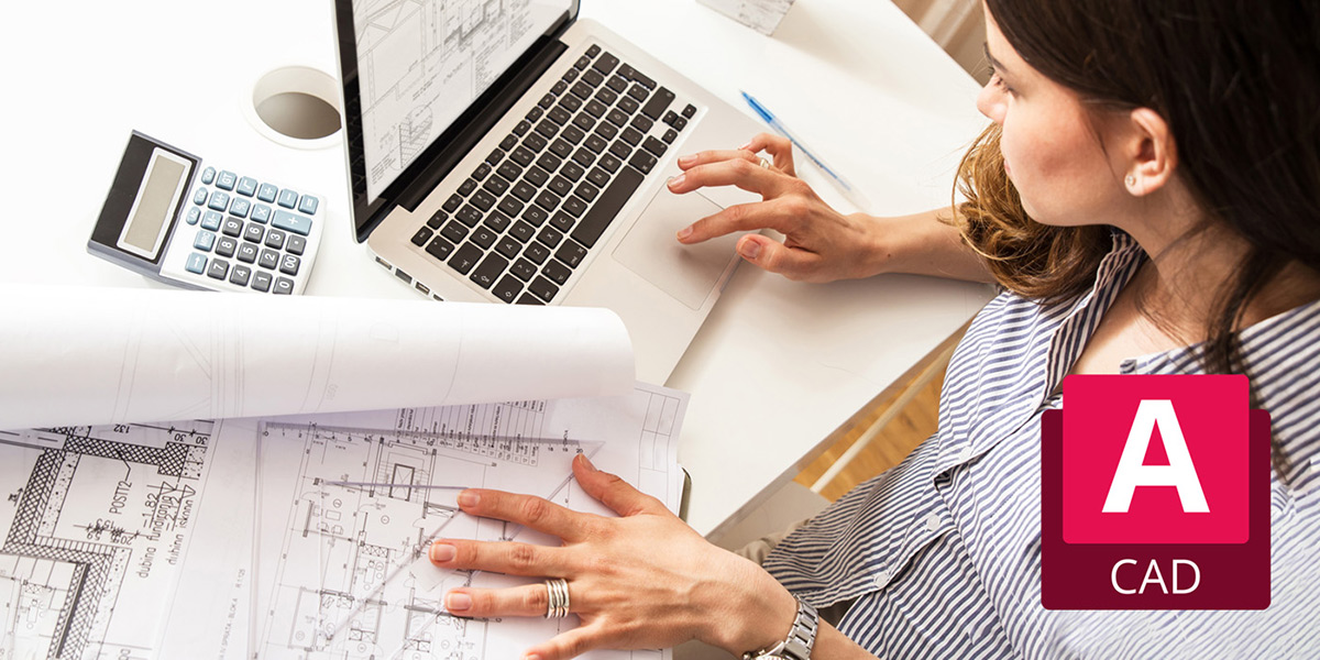 Overhead view of a woman working on a laptop, with blueprints spead out to her left.