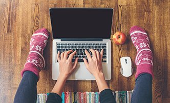 Overhead shot of a person sitting on the floor working on a laptop.