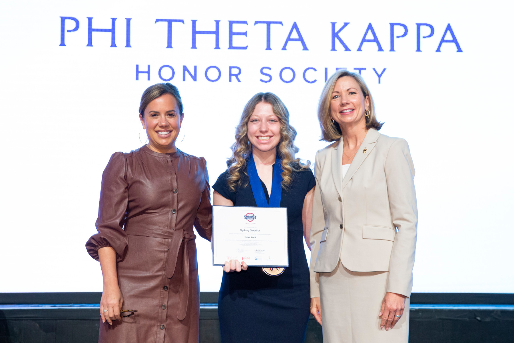 Sydney Swedick with standing on stage with reps from Coca-Cola Foundation and Phi Theta Kappa