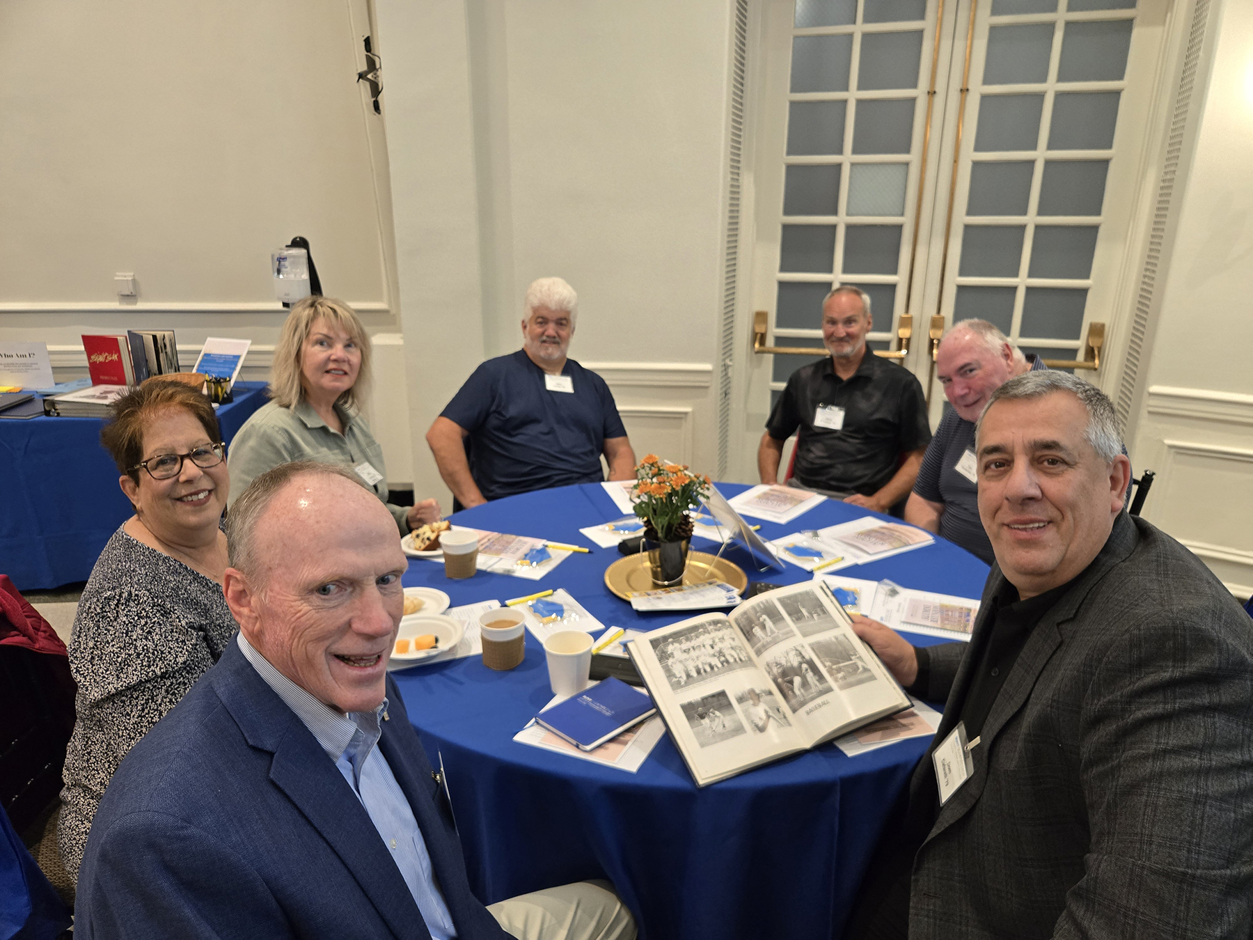 Alumni seated at table in Lally Mohawk Room, smiling