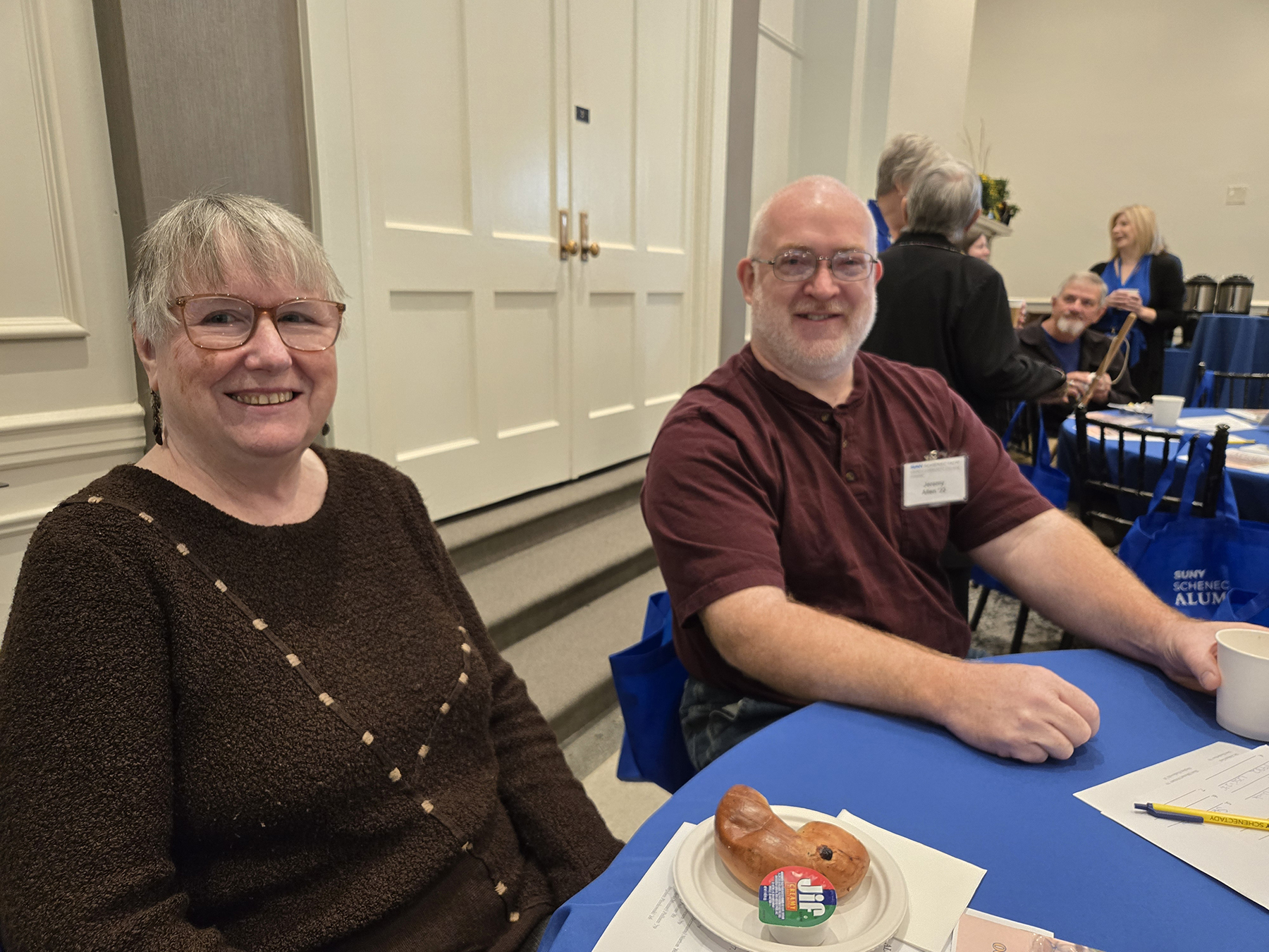 Alumni sitting at table in Lally Mohawk Room, smiling