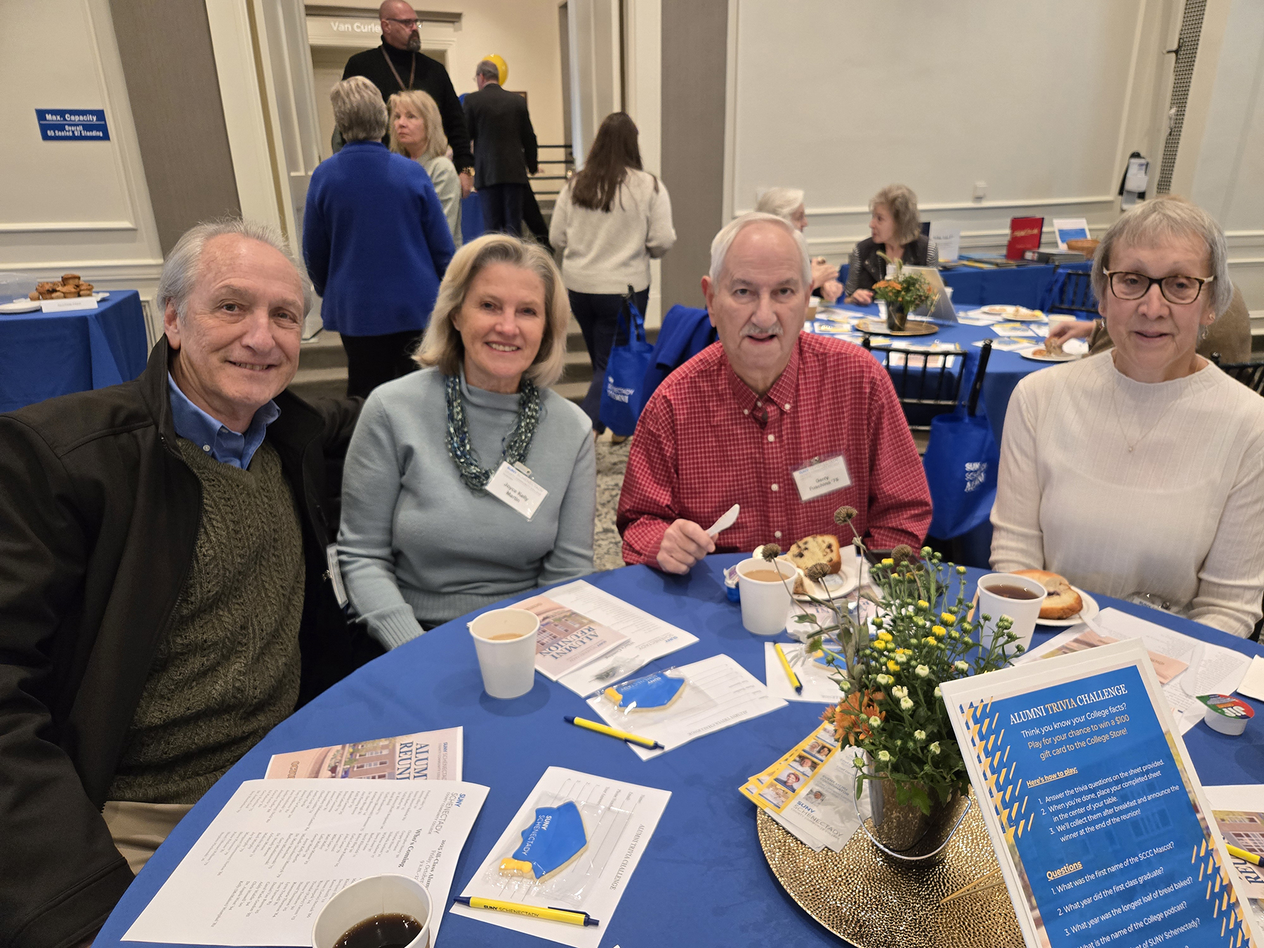 Alumni sitting at table in Lally Mohawk Room, smiling