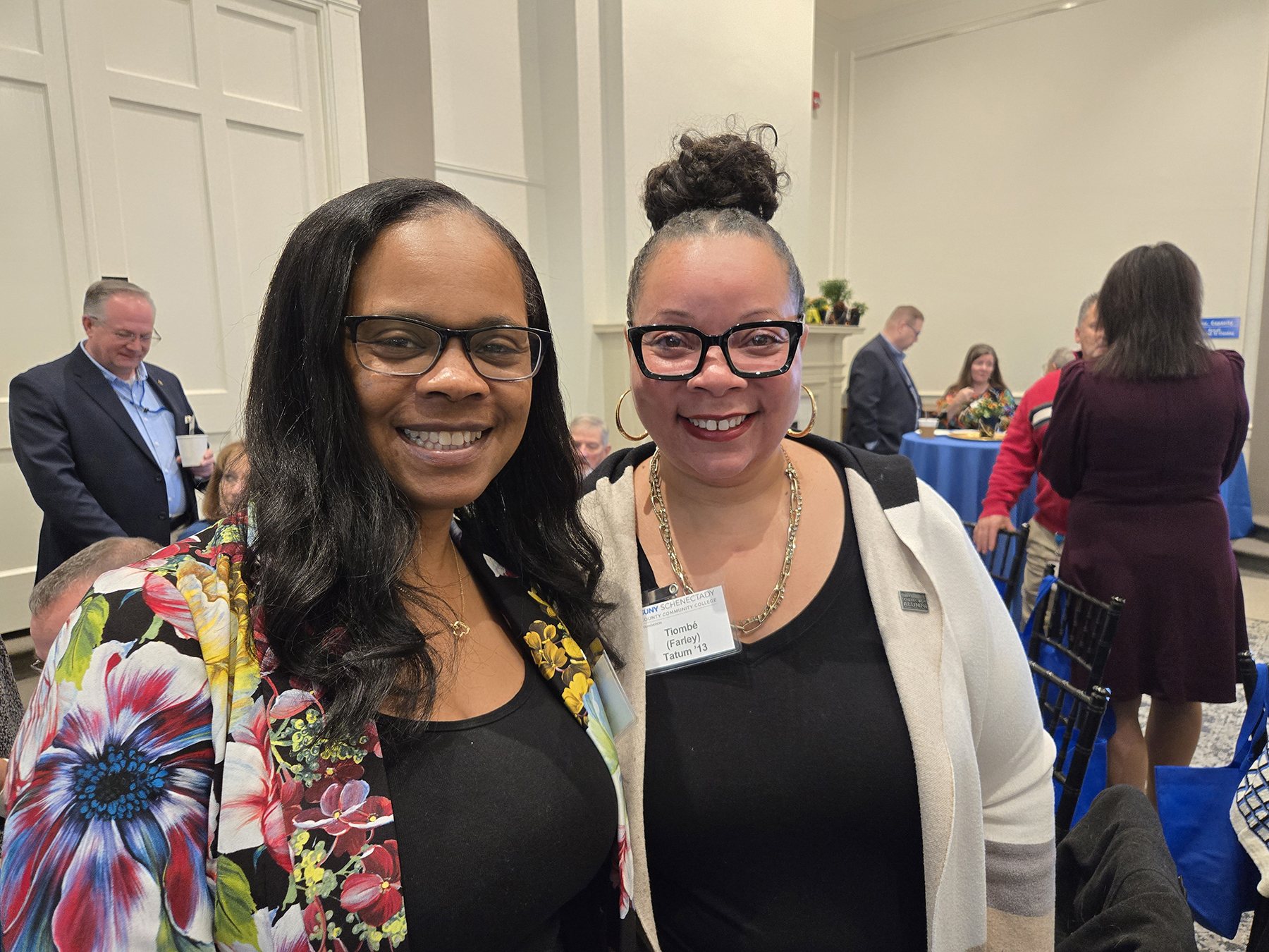 Two alumni standing in Lally Mohawk Room, smiling