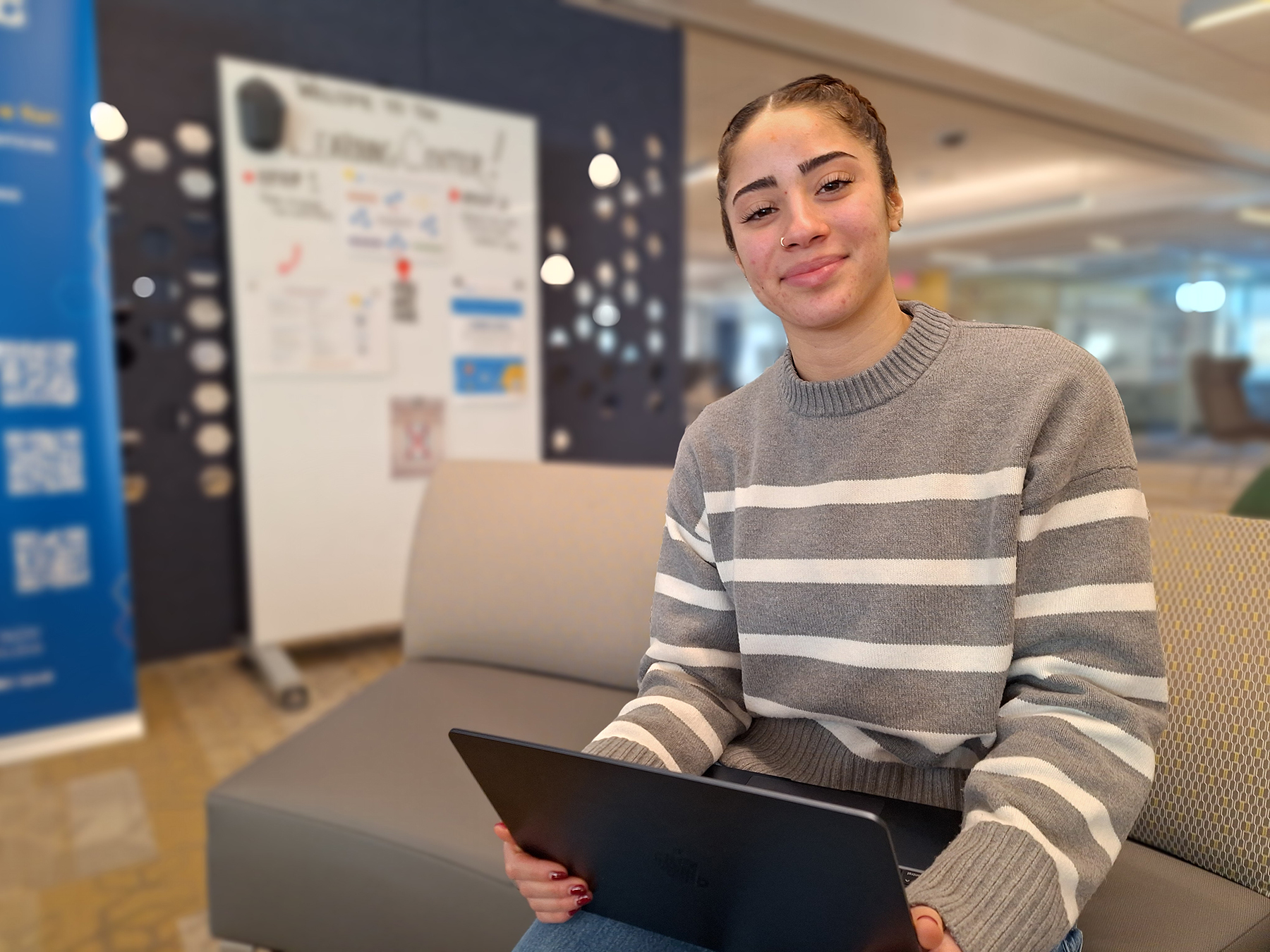 Ariana Matos sitting in library with laptop, smiling