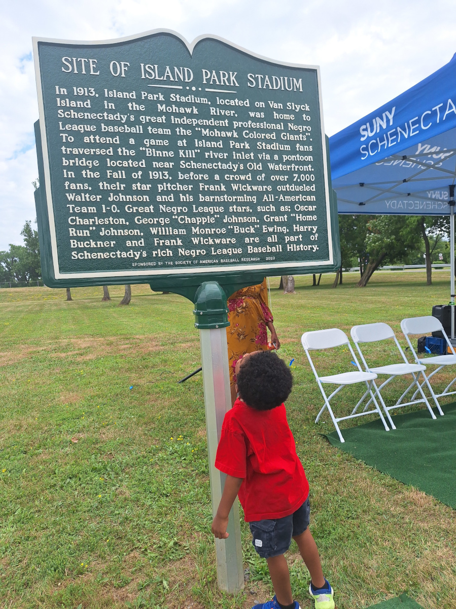 Child standing and looking up at historical marker