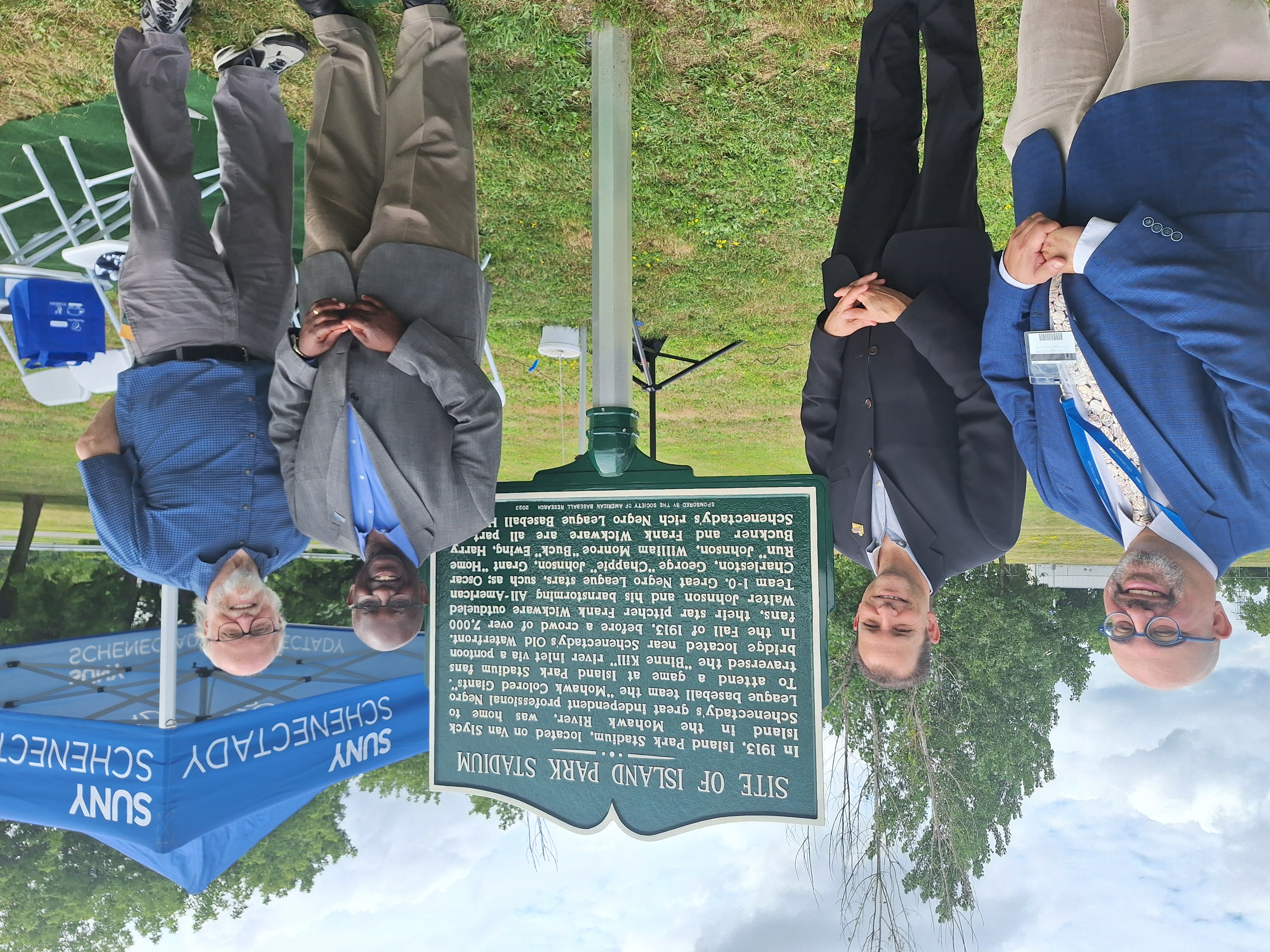 College, city, county historians standing near historical marker