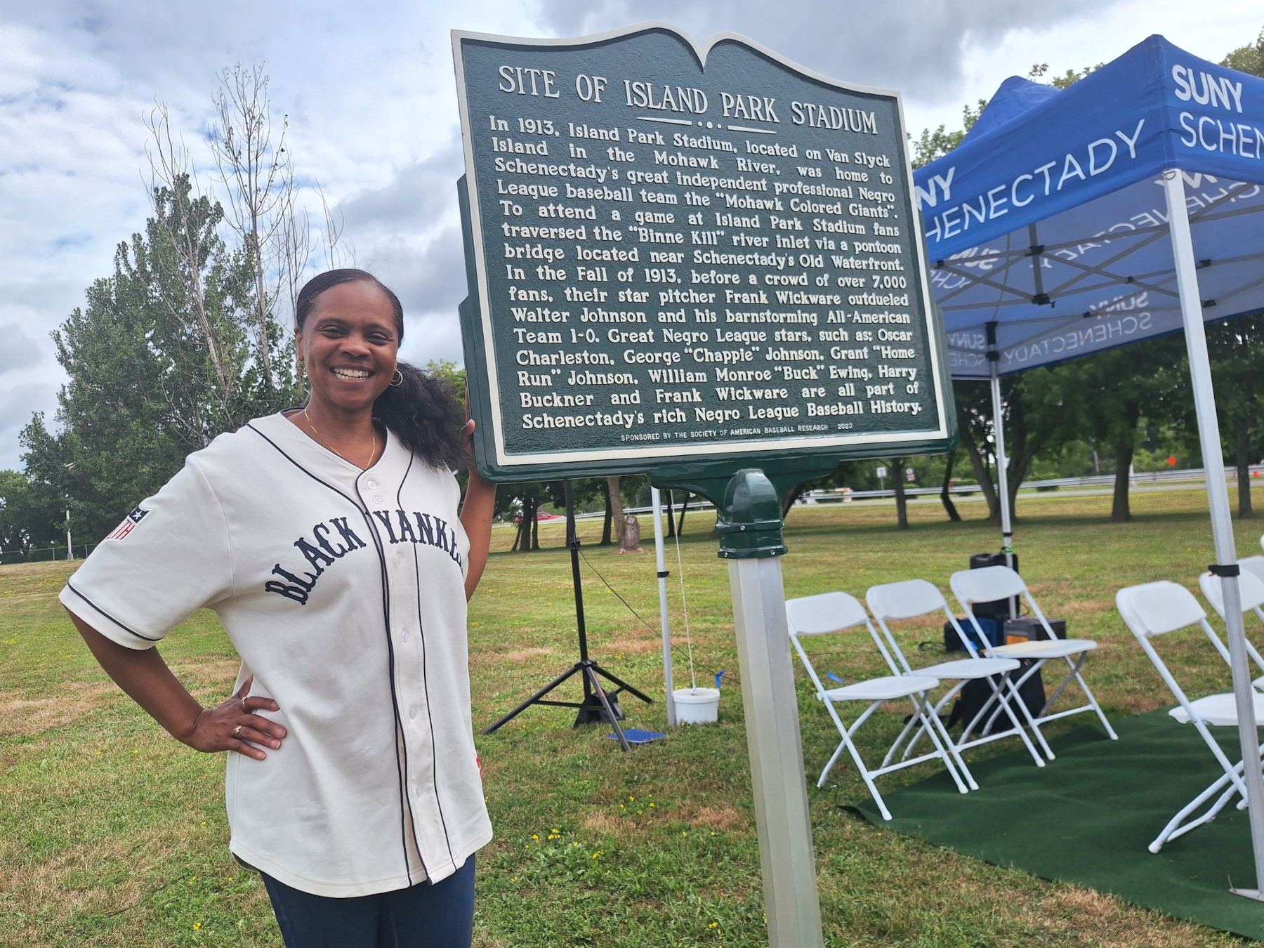 Wa'Kena Jackson standing, smiling in front of historical marker