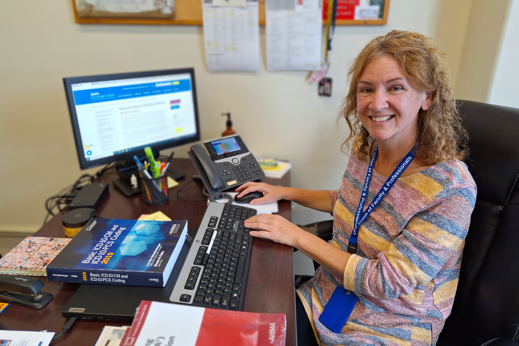 Carol Maimone sitting at her desk, smiling