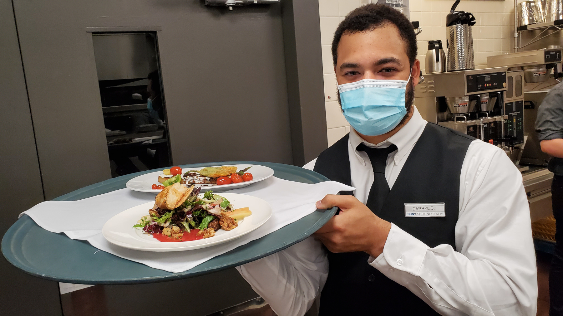 Student in uniform serving two plates of cuisine