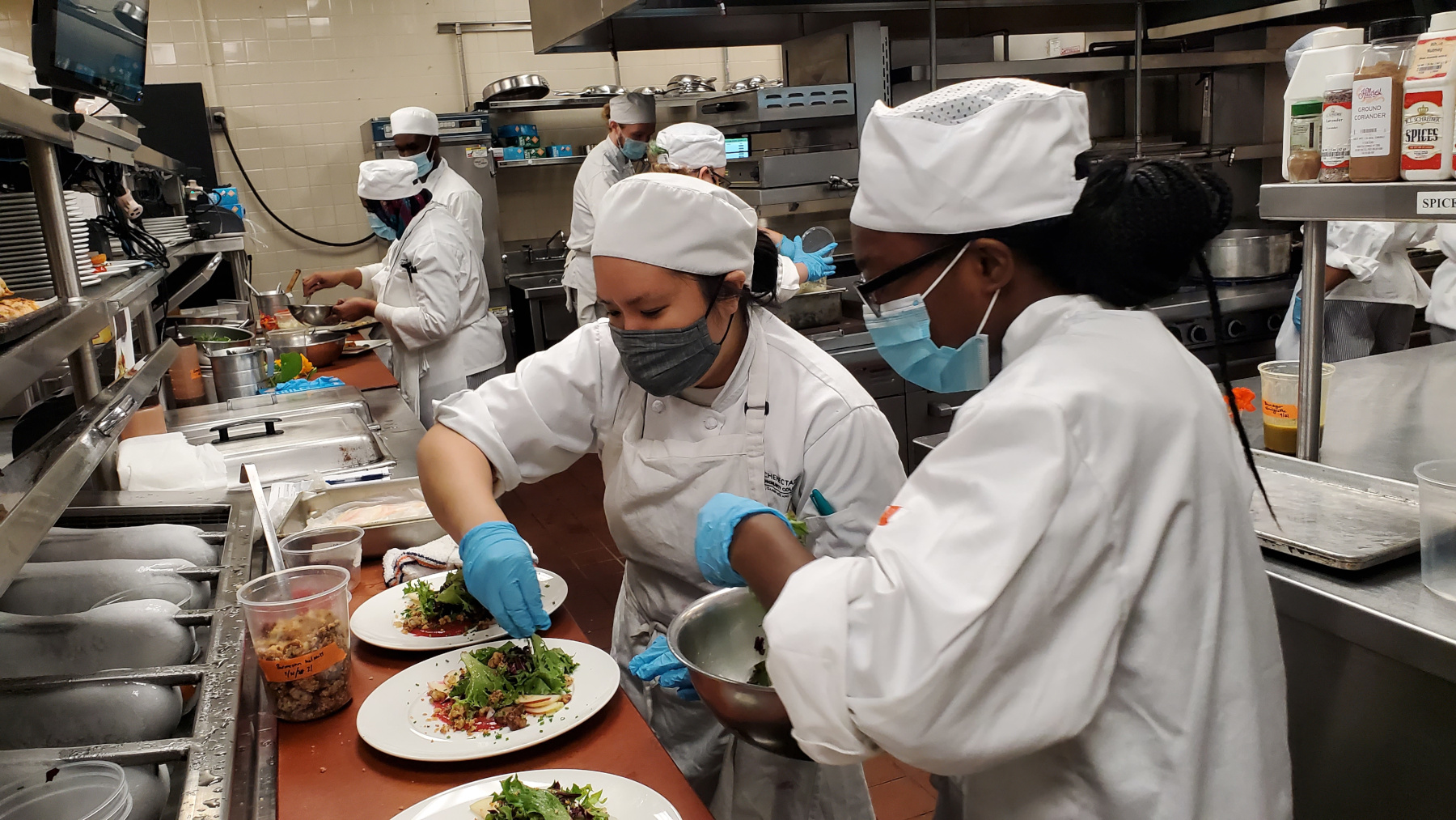 Students in uniform in lab preparing salads
