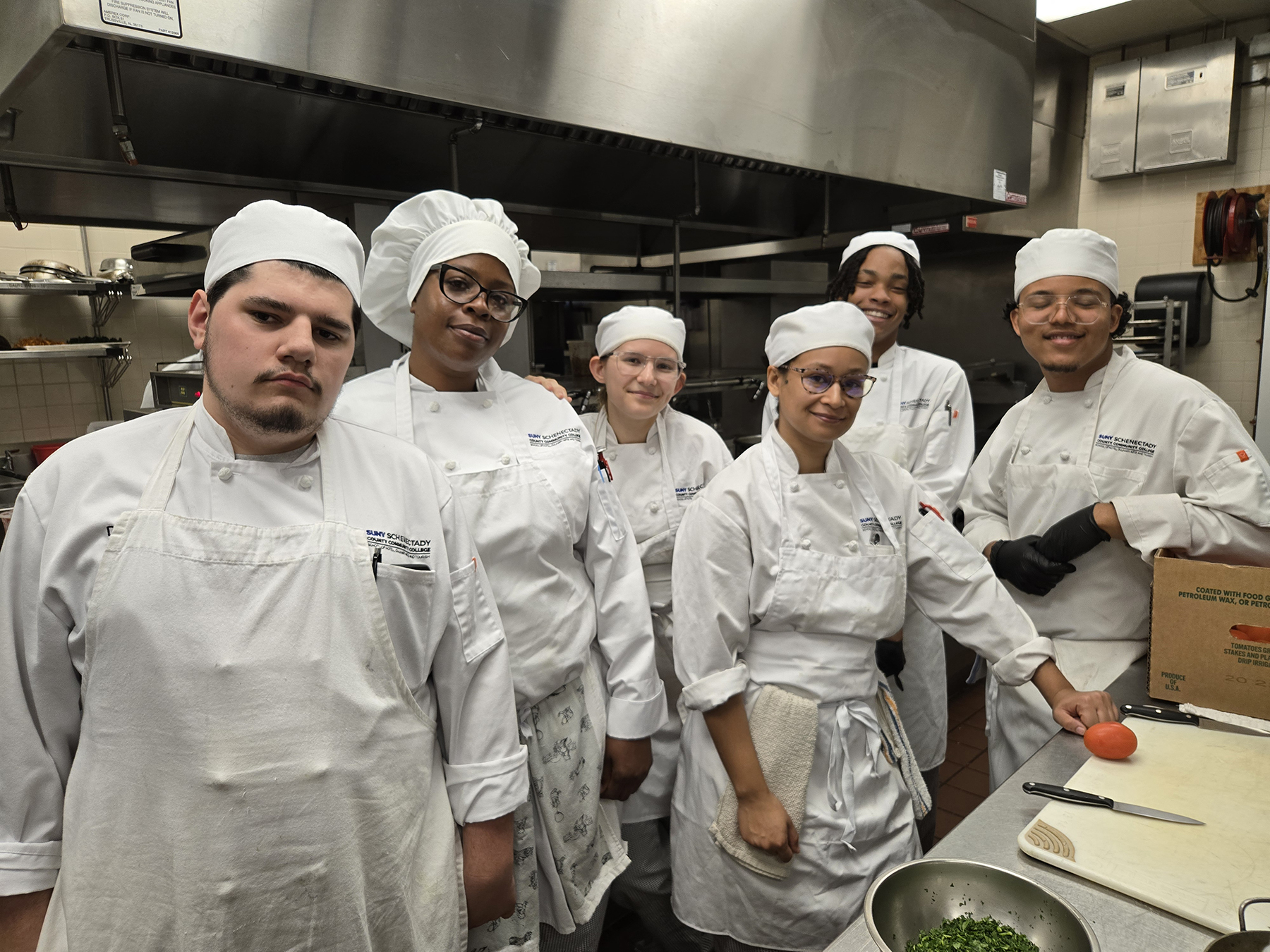 Student chefs in uniform standing in kitchen