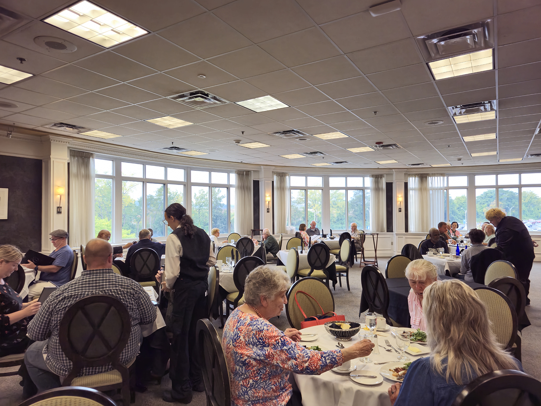 Inside the Casola Dining Room with tables full of patrons, student servers in uniform