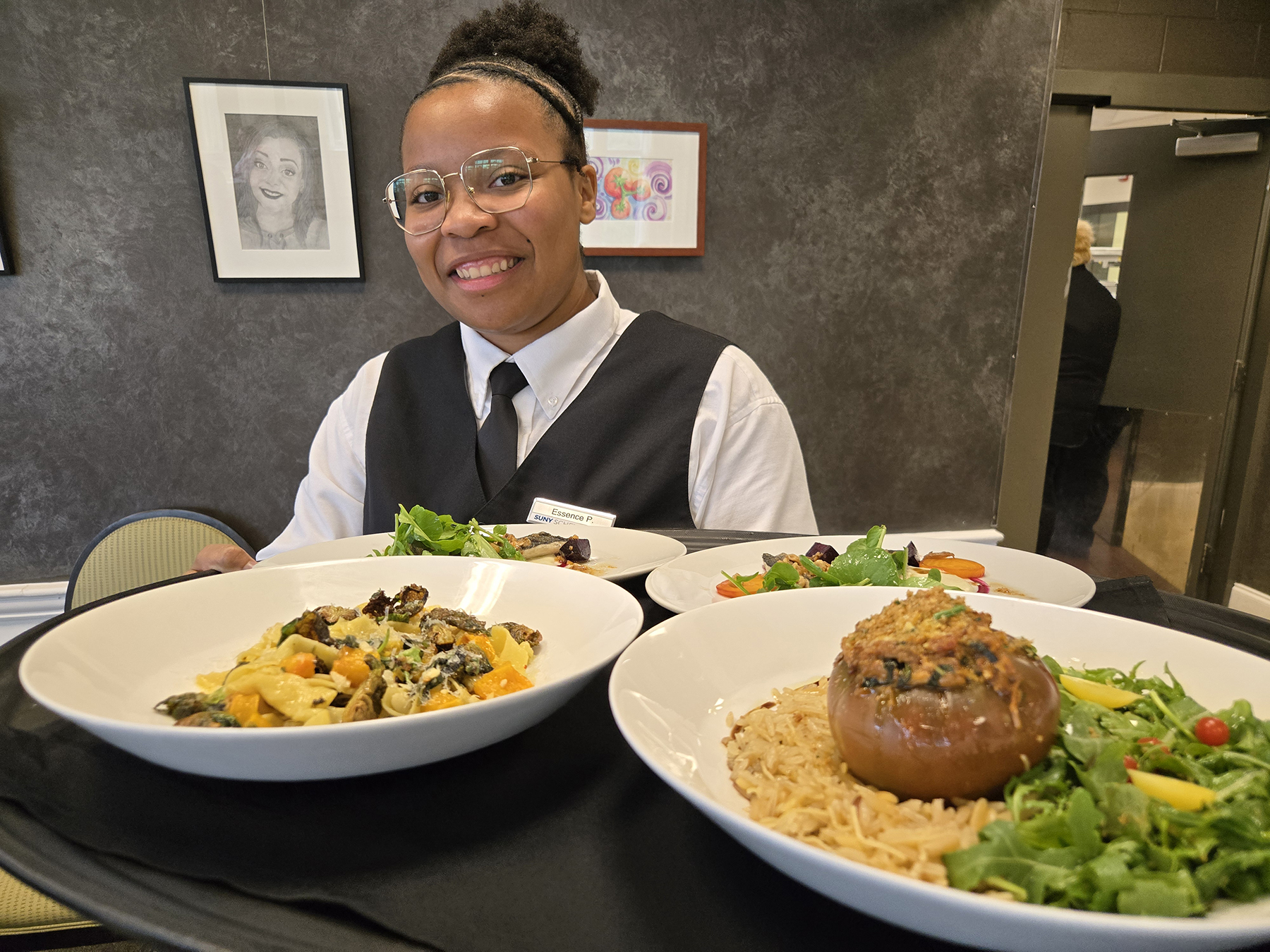 Student server holding tray with dishes of food inside Casola Dining Room